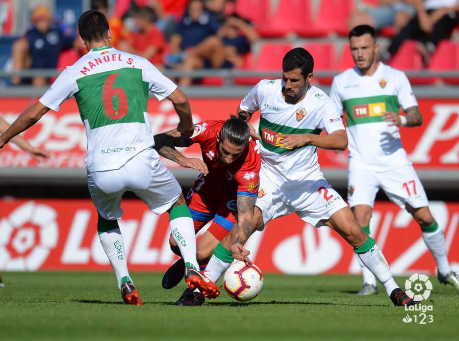 Los jugadores del Elche Tekio y Manuel Sánchez pelean un balón ante un rival del Numancia en el estadio Los Pajaritos / LFP