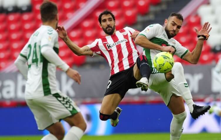 Gonzalo Verdú y Raúl García pelean un balón durante un partido entre Elche y Athletic / LaLiga